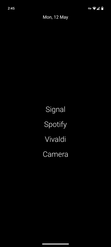 Phone home screen screenshot of white text on a black background. Today’s date is at the top just below the status bar. Four app names are in the center: Signal, Spotify, Vivaldi, and Camera.
