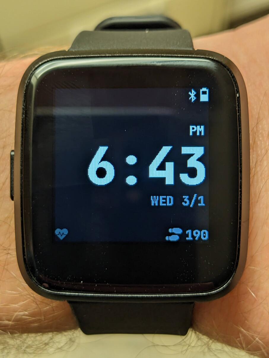 A closeup photo of a Pinetime smart watch with a lightly modified defaut digital watch face.
